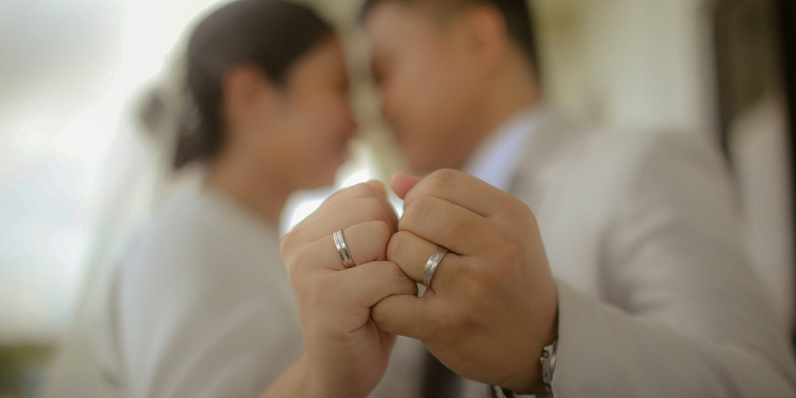 A couple holding up wedding rings.